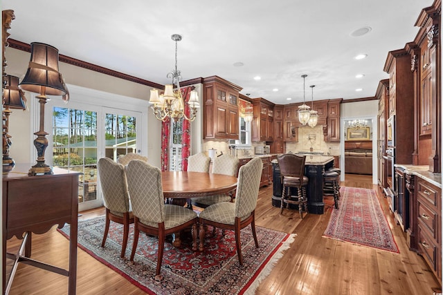 dining area with an inviting chandelier, recessed lighting, light wood-style floors, and ornamental molding