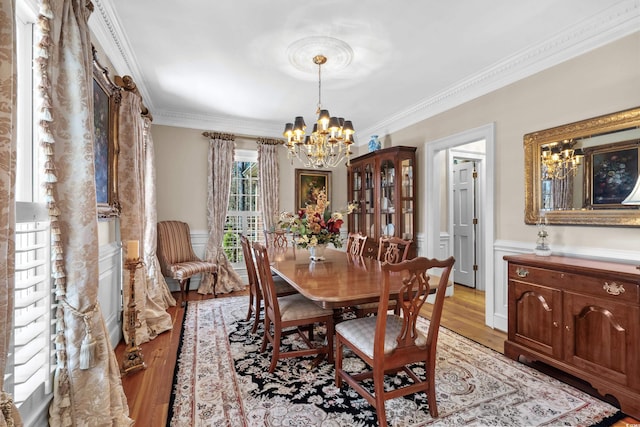 dining room featuring light wood-type flooring, a notable chandelier, and ornamental molding