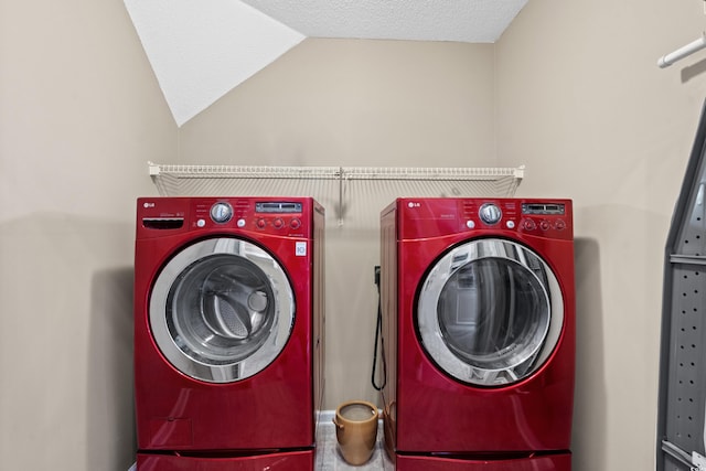 washroom featuring a textured ceiling, laundry area, and washing machine and clothes dryer