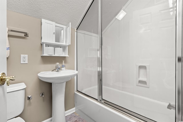 bathroom featuring baseboards, shower / bath combination with glass door, a sink, a textured ceiling, and toilet