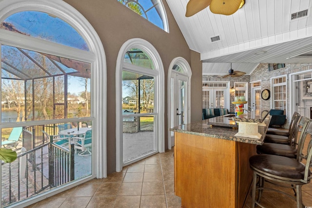 kitchen featuring dark stone countertops, a ceiling fan, visible vents, and vaulted ceiling