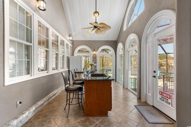 sunroom with a sink, a ceiling fan, and vaulted ceiling