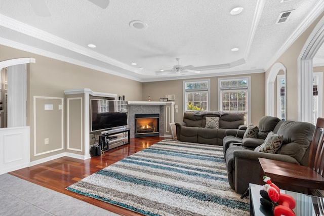 living room with arched walkways, a raised ceiling, ceiling fan, and dark wood finished floors