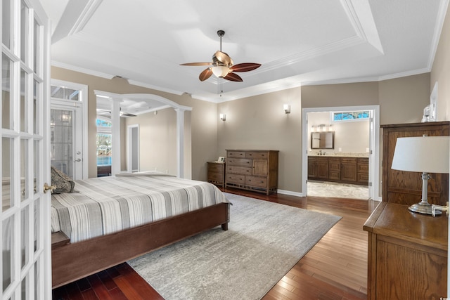 bedroom with ornate columns, a raised ceiling, crown molding, and hardwood / wood-style flooring