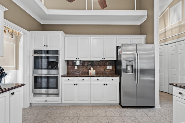 kitchen featuring a ceiling fan, backsplash, appliances with stainless steel finishes, white cabinets, and crown molding