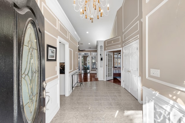 entryway featuring light tile patterned flooring, recessed lighting, ornamental molding, french doors, and a chandelier