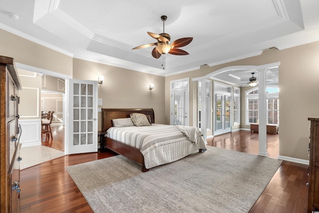 bedroom with a raised ceiling, french doors, wood-type flooring, and ornamental molding