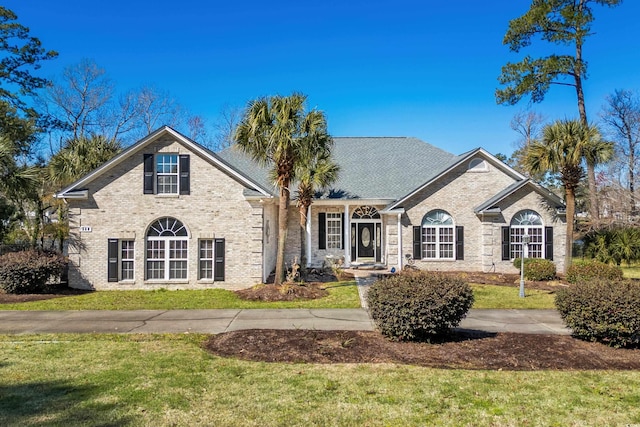 traditional home featuring brick siding and a front lawn