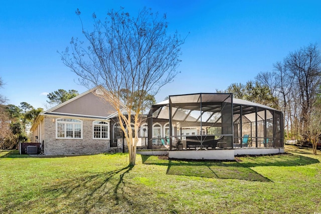 back of property featuring cooling unit, a lawn, a lanai, and brick siding