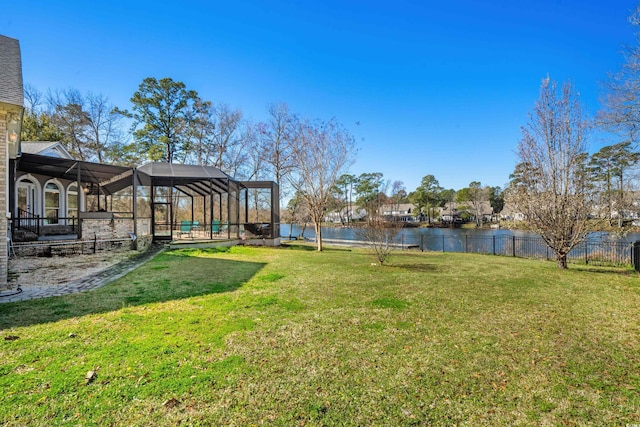 view of yard with glass enclosure, fence, and a water view