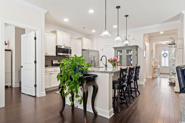 kitchen with a breakfast bar area, light stone counters, dark wood-style floors, stainless steel appliances, and backsplash