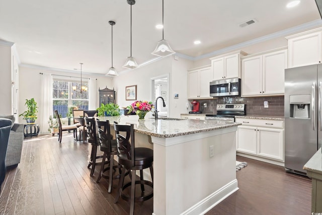 kitchen with visible vents, crown molding, decorative backsplash, stainless steel appliances, and a sink