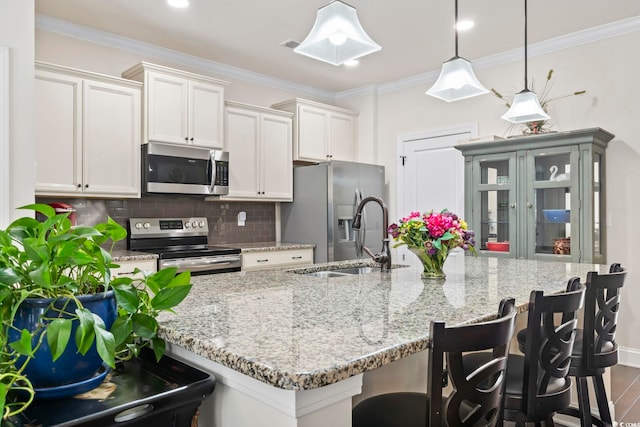 kitchen featuring backsplash, crown molding, a kitchen breakfast bar, stainless steel appliances, and a sink