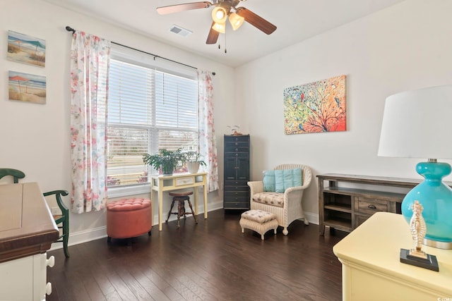 living area featuring hardwood / wood-style floors, baseboards, visible vents, and a ceiling fan