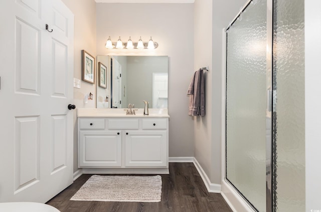 full bath with baseboards, wood finished floors, a stall shower, and vanity