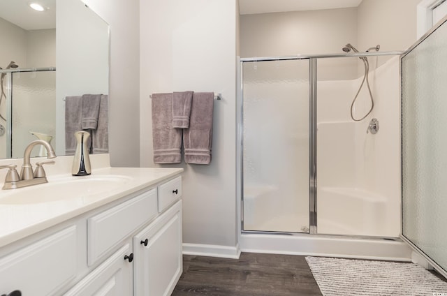 bathroom featuring baseboards, wood finished floors, a stall shower, and vanity