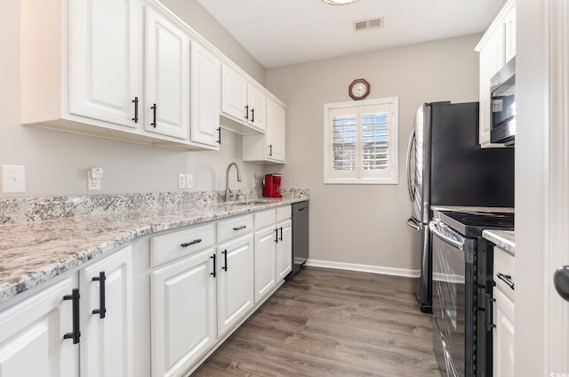 kitchen featuring visible vents, stainless steel microwave, electric range oven, white cabinets, and a sink