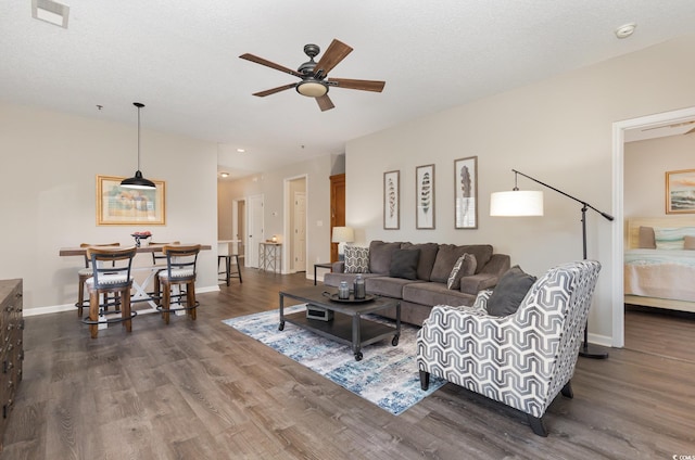 living area featuring visible vents, baseboards, dark wood-type flooring, and ceiling fan