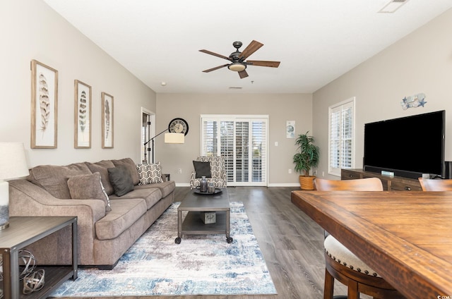 living room with visible vents, wood finished floors, baseboards, and ceiling fan