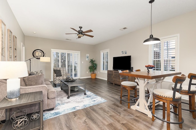 living area with baseboards, wood finished floors, visible vents, and ceiling fan