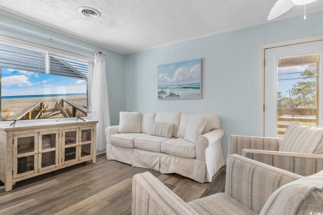 living room featuring a ceiling fan, wood finished floors, visible vents, and a textured ceiling