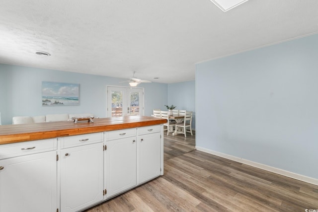 kitchen featuring light wood-style flooring, white cabinetry, butcher block counters, baseboards, and ceiling fan