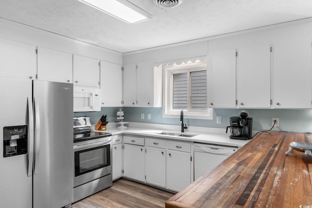 kitchen with white cabinetry, butcher block counters, stainless steel appliances, and a sink