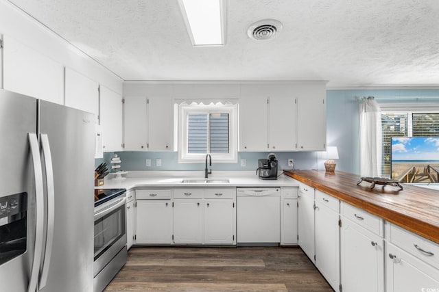 kitchen with a sink, stainless steel appliances, white cabinets, and dark wood-style flooring