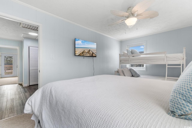 bedroom with ceiling fan, a textured ceiling, wood finished floors, and ornamental molding