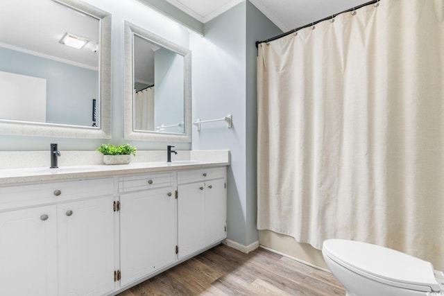 bathroom with a sink, toilet, wood finished floors, and crown molding