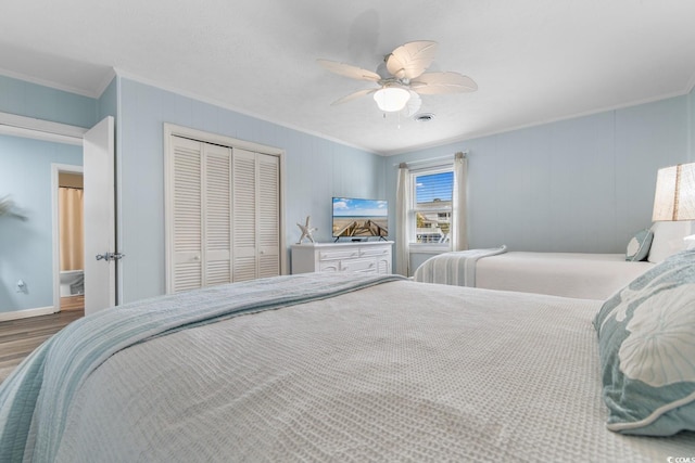 bedroom with a ceiling fan, wood finished floors, visible vents, a closet, and crown molding