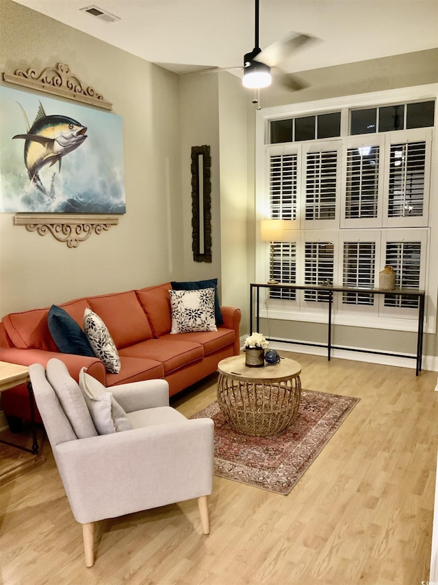 living area featuring a ceiling fan, wood finished floors, and visible vents