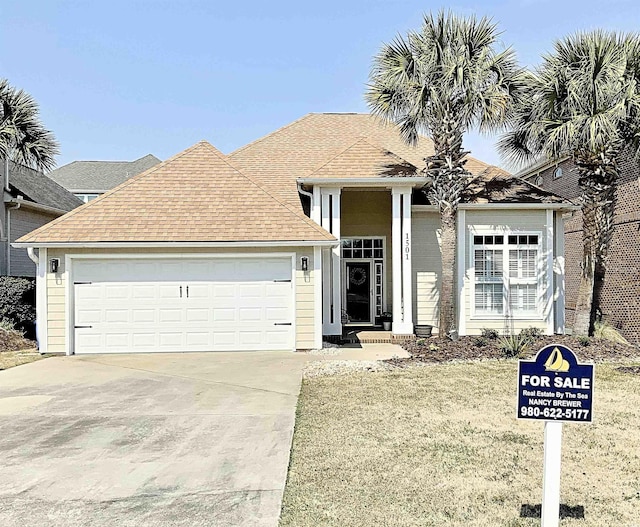 view of front of house with roof with shingles, concrete driveway, and an attached garage