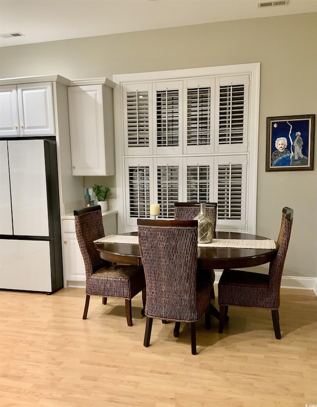 dining room featuring baseboards, visible vents, and light wood-type flooring