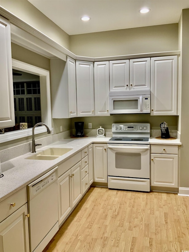 kitchen with light wood-style flooring, a sink, light stone counters, recessed lighting, and white appliances