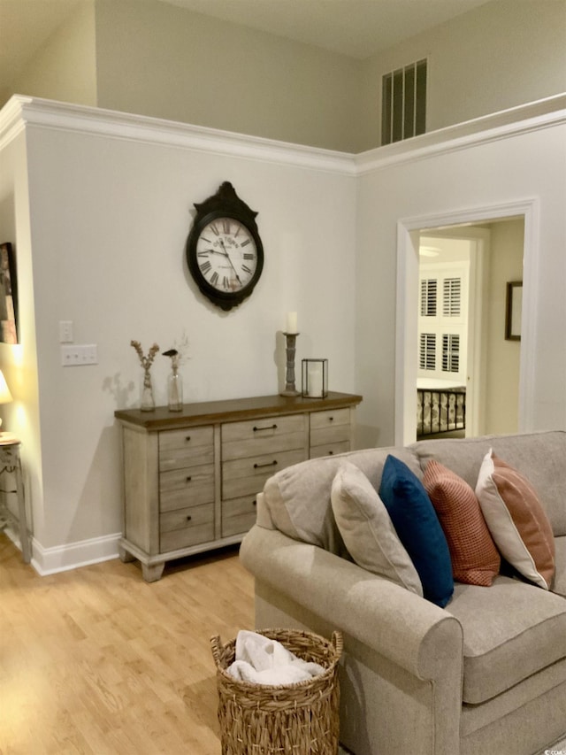 living room featuring visible vents, baseboards, light wood-style floors, and a high ceiling