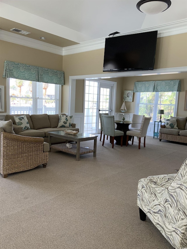 carpeted living room with visible vents, a wealth of natural light, and ornamental molding