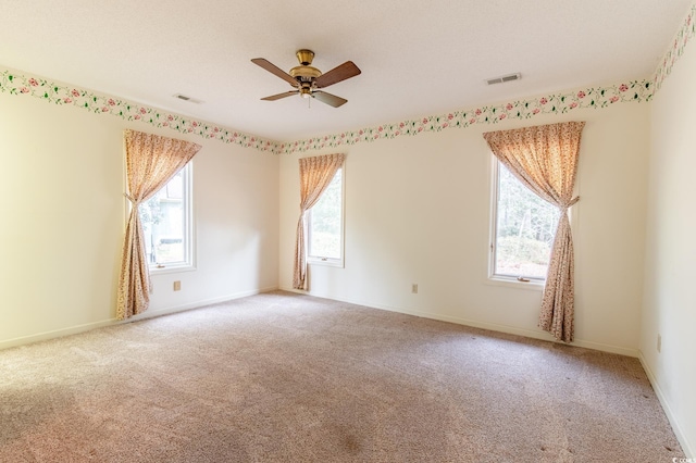 empty room featuring ceiling fan, baseboards, visible vents, and light carpet