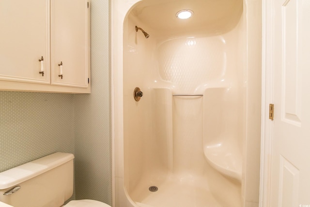 bathroom with toilet, a walk in shower, and wallpapered walls