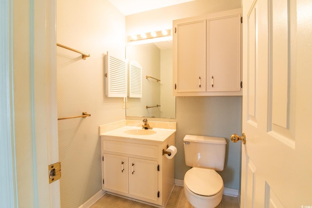 half bath with baseboards, toilet, and vanity