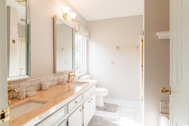 bathroom with a sink, toilet, double vanity, and tile patterned floors