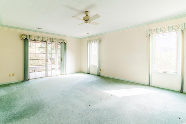 carpeted empty room with crown molding, a ceiling fan, baseboards, and visible vents