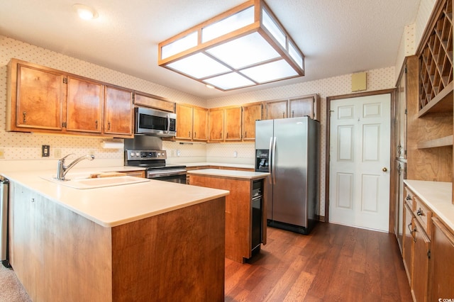 kitchen featuring wallpapered walls, a sink, stainless steel appliances, light countertops, and a center island