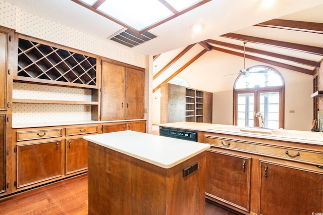 kitchen with a center island, visible vents, brown cabinets, and vaulted ceiling with beams