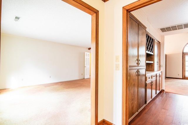 corridor featuring hardwood / wood-style floors, carpet, baseboards, and visible vents