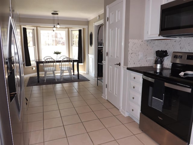 kitchen featuring light tile patterned floors, white cabinets, stainless steel appliances, and crown molding