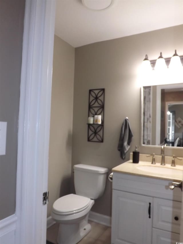 bathroom featuring vanity, toilet, baseboards, and tile patterned flooring