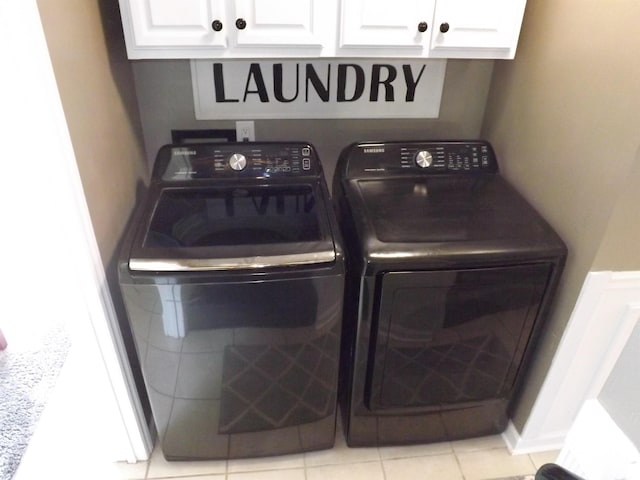 laundry room featuring light tile patterned floors, cabinet space, and washing machine and clothes dryer