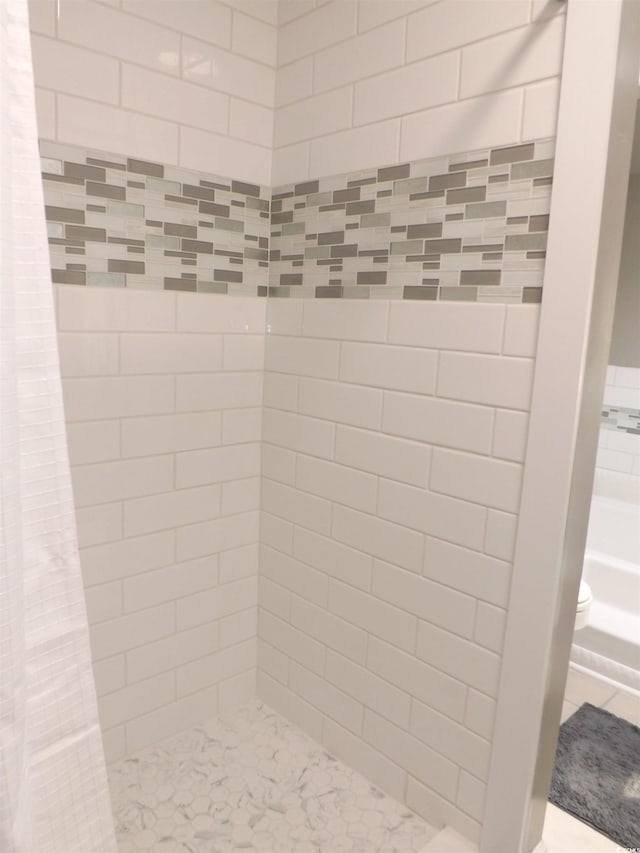 bathroom with a tile shower and toilet