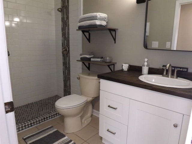 full bathroom with tile patterned flooring, toilet, vanity, and tiled shower